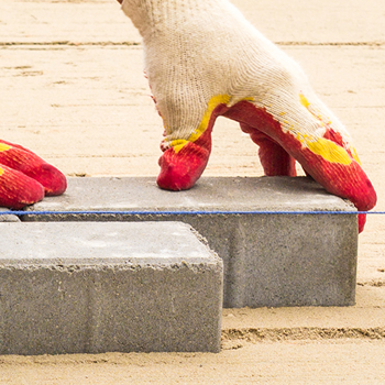 Hands laying paving stones